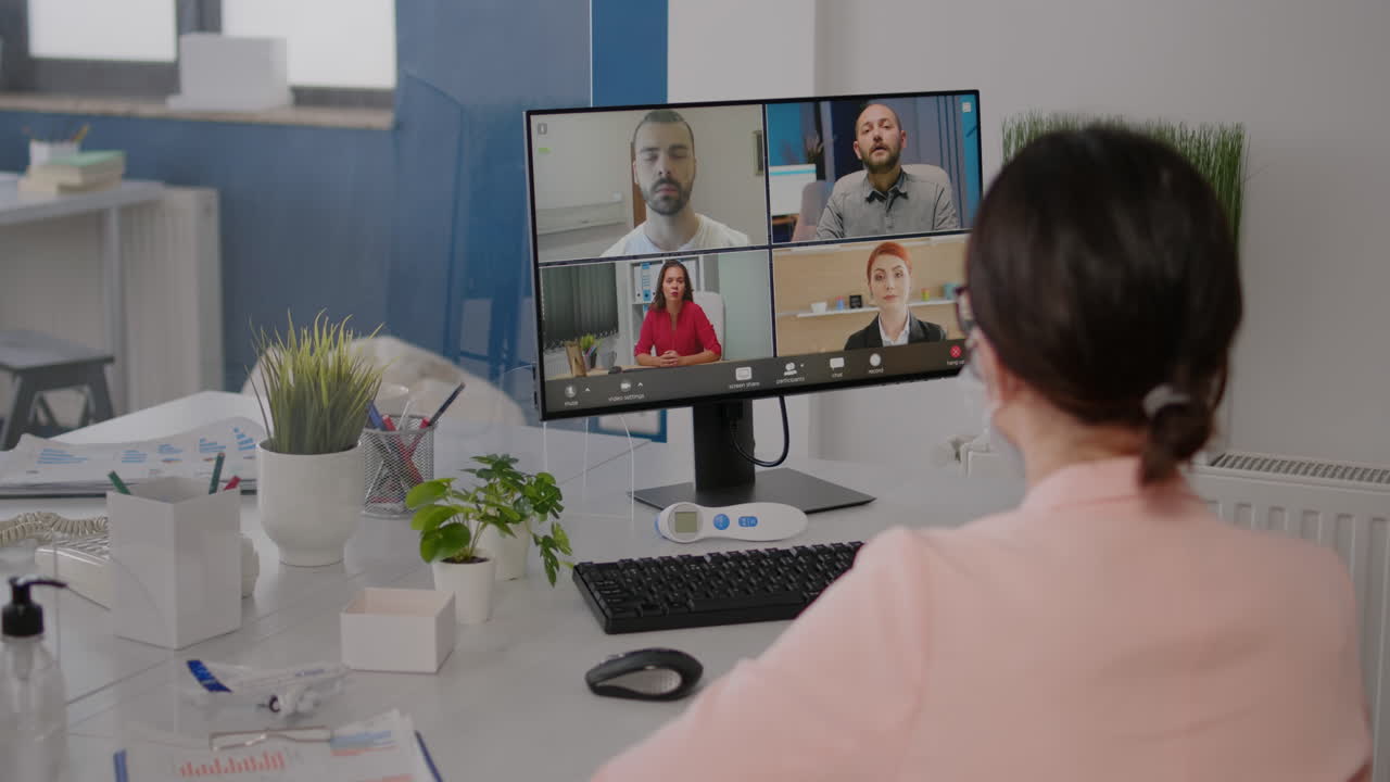 Executive freelancer looking into monitor talking with coworkers on online videocall