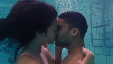 young couple kissing underwater in swimming pool enjoying intimate kiss romantic lovers submerged in water floating with bubbles in passionate intimacy