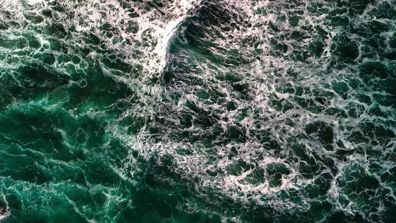 Slow motion, aerial, birds eye view, drone shot of colourful, powerful, large, crashing waves with white caps
