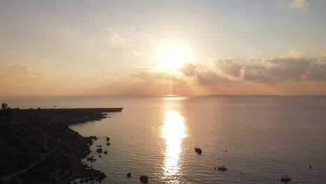 aerial drone shot rising over konnos bay coast with golden sunset