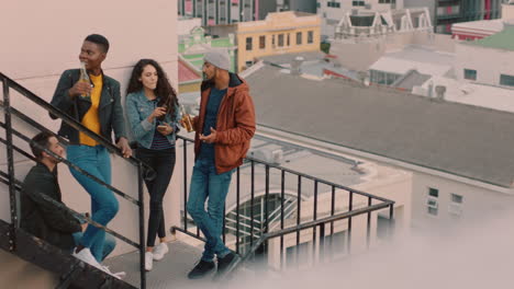 group of friends relaxing on fire escape stairs enjoying rooftop party chatting sharing excitement for weekend celebration in city