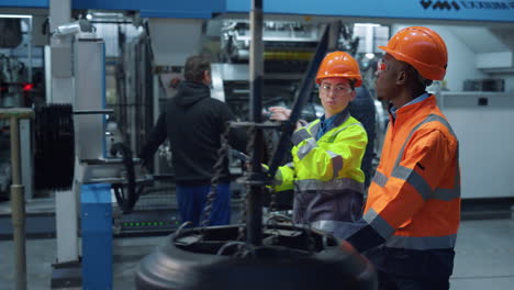 focused colleagues discussing project work at huge modern special factory.