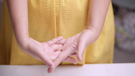 estirando sus manos y dedos, la mujer está tratando de aliviarse de la inflamación y el dolor que está sintiendo