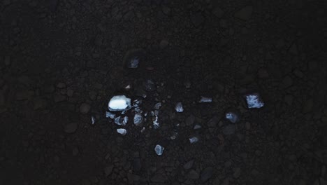 TOP-DOWN-aerial-footage-of-some-exposed-snow-covered-rocks-lifting-up-to-reveal-the-shallow-rocky-bottom-surrounding