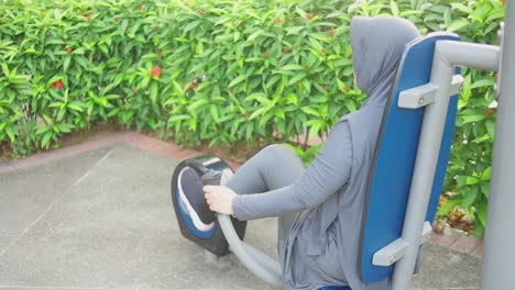 Young-Muslim-Woman-Wear-Hijab-Using-Exercise-Bike-In-Public-Park