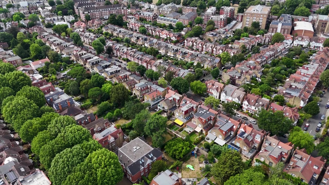 Una fitta rete di strade a schiera e giardini posteriori si estende attraverso un verdeggiante sobborgo di Londra ovest verso un'area verde aperta.