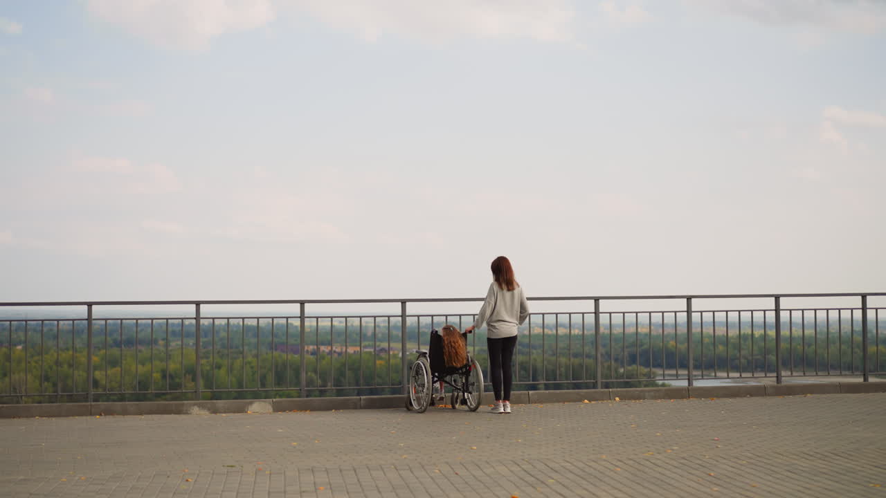 madre muestra el río y el parque a su hija con parálisis cerebral