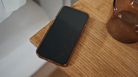 Closeup smartphone wooden table in ambient bedroom setting. Locked smart device