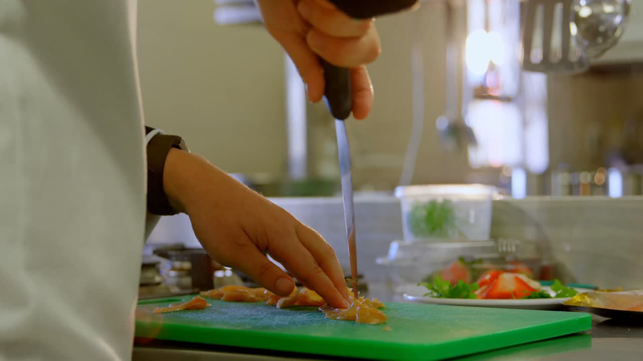 요리사 가 주방 4k 에서  ⁇ 기 보드 에 고기 를 자르고 있다
