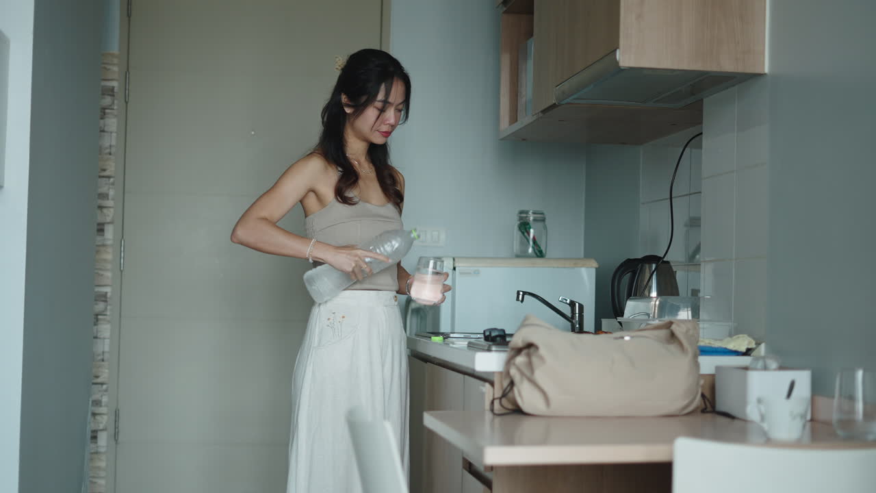 Una donna in cucina beve acqua