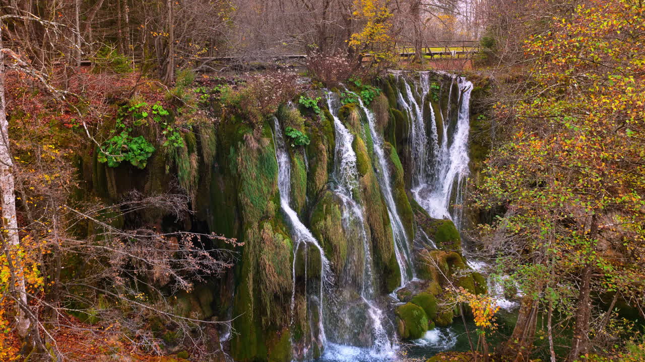 Vista aerea da drone di cascate a gradoni che scorrono su scogliere coperte di muschio e vegetazione lussureggiante nel Parco nazionale dei laghi di Plitvice, Croazia