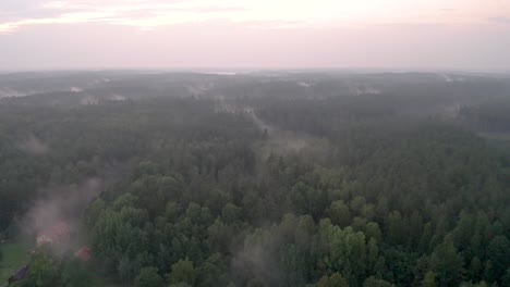 Drone-flight-over-a-foggy-forest-during-sunset