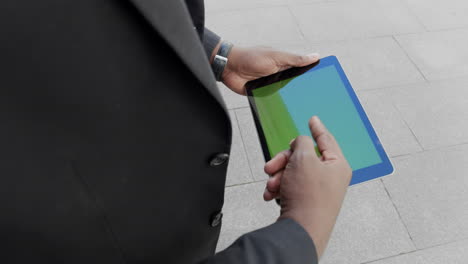 businessman scrolling tablet on street. entrepreneur working on pad outdoors