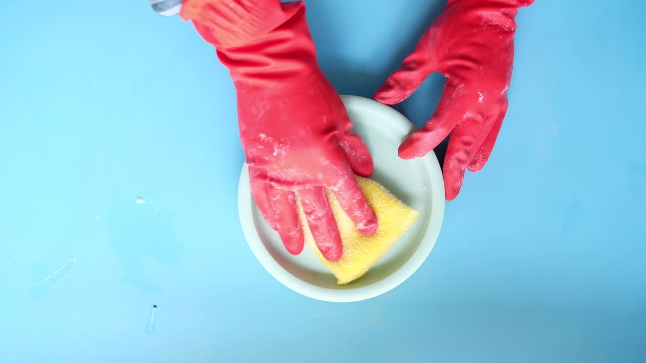 limpiando un plato con guantes y esponja