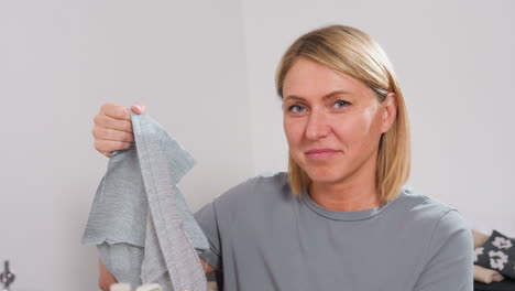 garment maker holding piece of material sewed on mechanical sewing machine, proudly displaying finished section, smiling with satisfaction, verifying stitching quality, showing professional skill