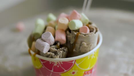 delicious rolled ice cream with colorful marshmallows and caramel sauce