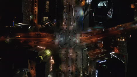 Aerial-birds-eye-overhead-top-down-ascending-shot-of-traffic-in-night-city.-Cars-driving-through-road-intersection.-Warsaw,-Poland
