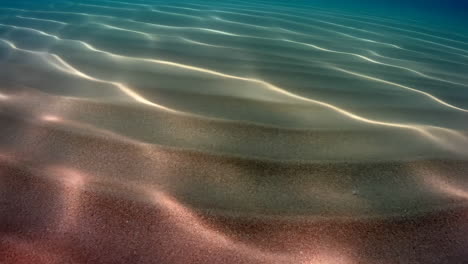 underwater sand ripples with sunlight patterns