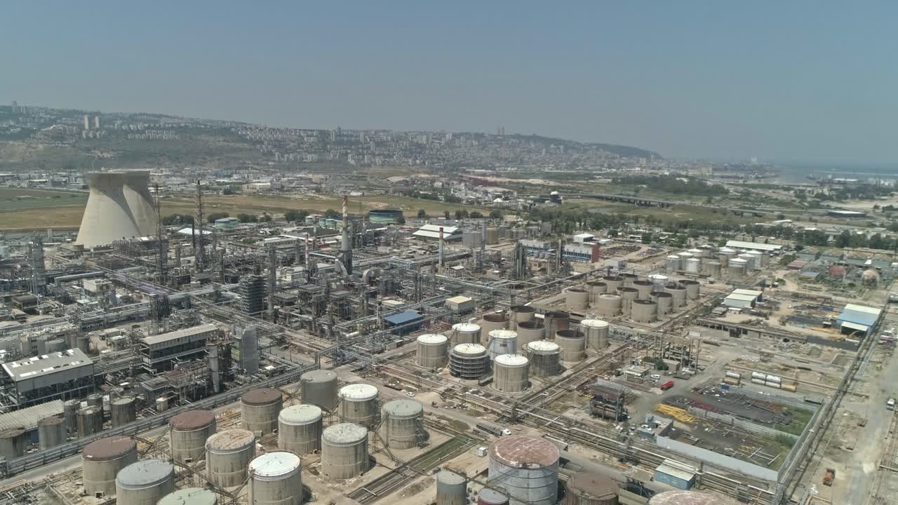 Aerial footage of a large scale Oil refinery with smoke stacks and petroleum storage tanks