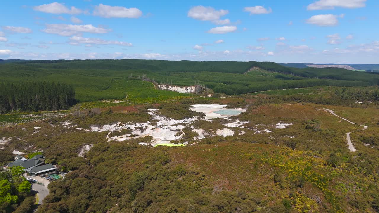 Letecký záběr: Termální ráj Waiotapu během dne na jižním konci vulkanického centra Okataina, Nový Zéland, záběr dronem s výjezdem vzhůru.