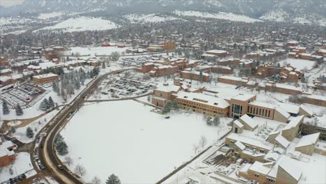 aerial flyover snowy cityscape of boulder with university during winter