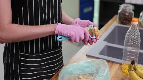 person peeling potatoes with a peeler in a kitchen