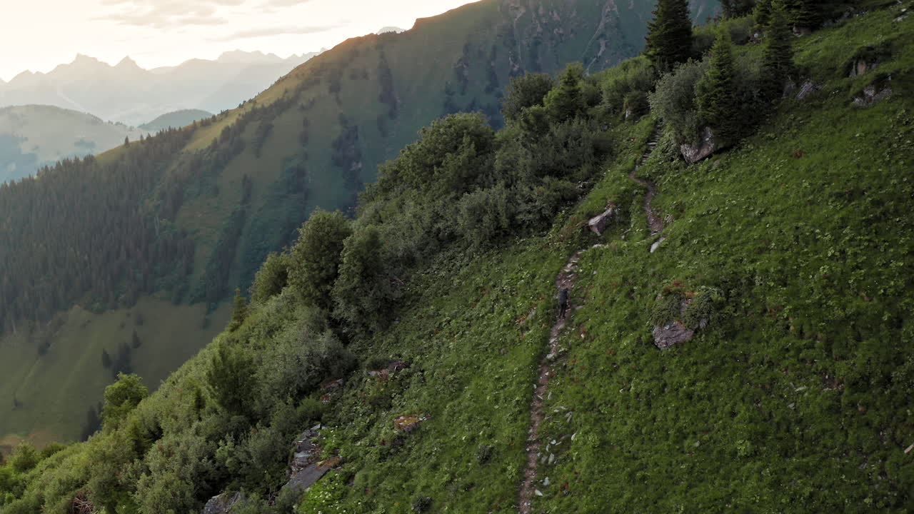 vista de pájaro del caminante solitario caminando por el sendero de la montaña al amanecer