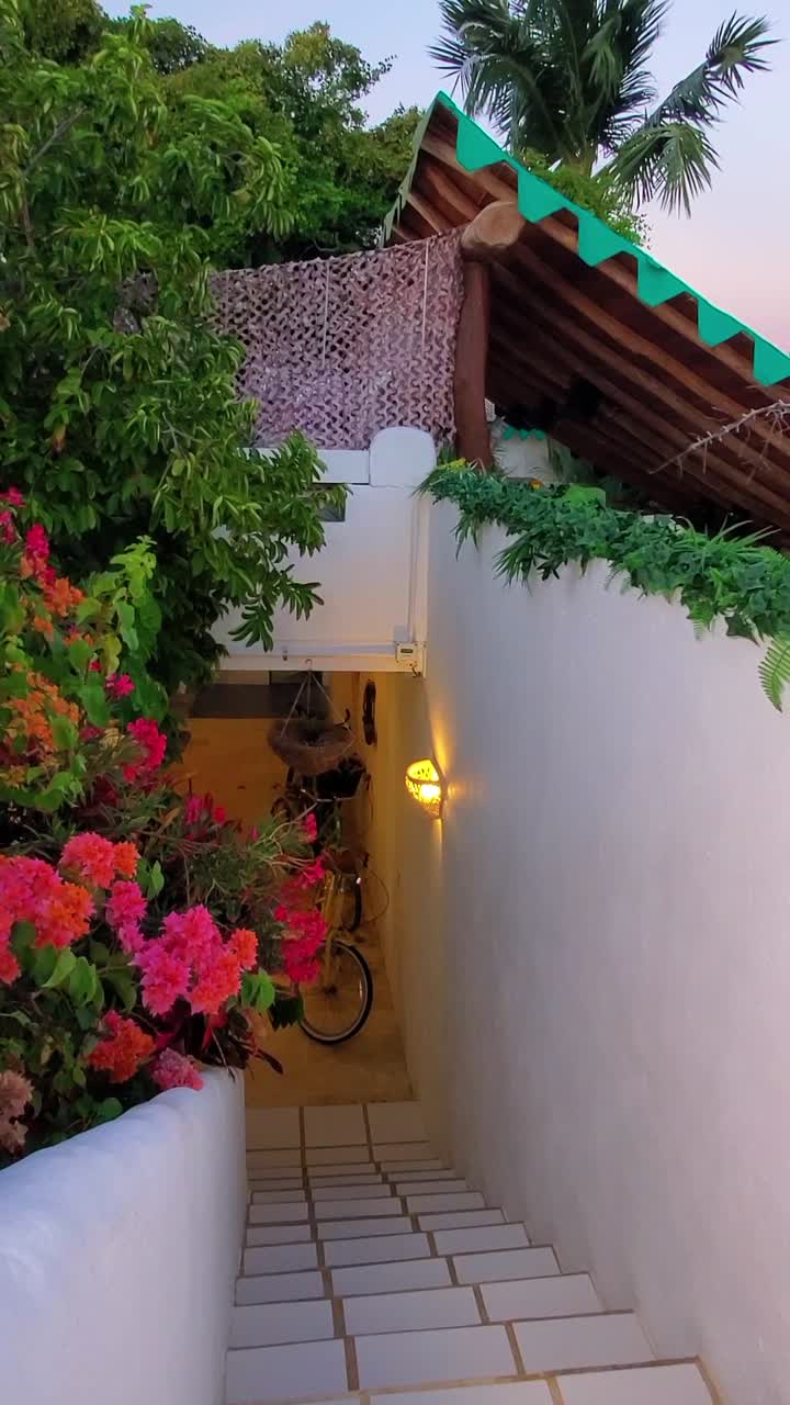 An enchanting view of a tropical outdoor terrace adorned with vibrant flowers. The warm glow of sunset enhances the peaceful atmosphere as steps lead downwards, inviting exploration.