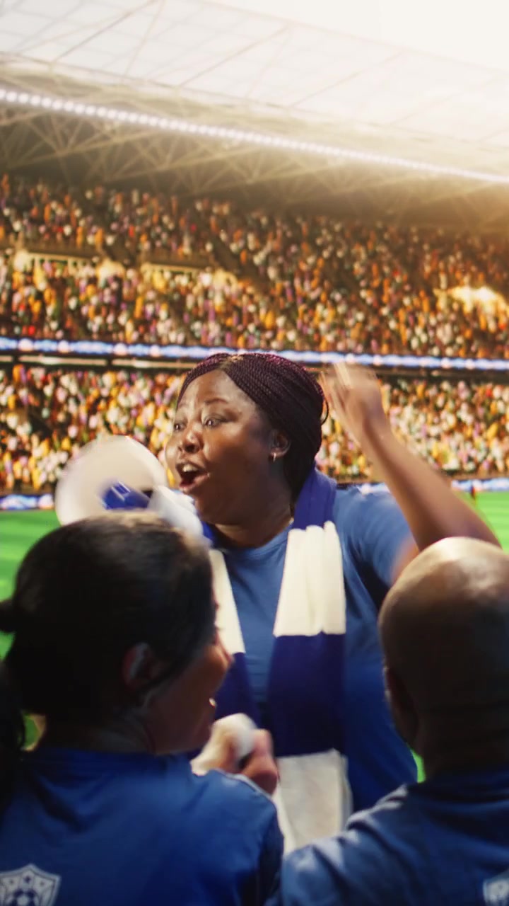 Video vertical: Mujer entusiasta en un estadio de fútbol gritando por un megáfono.