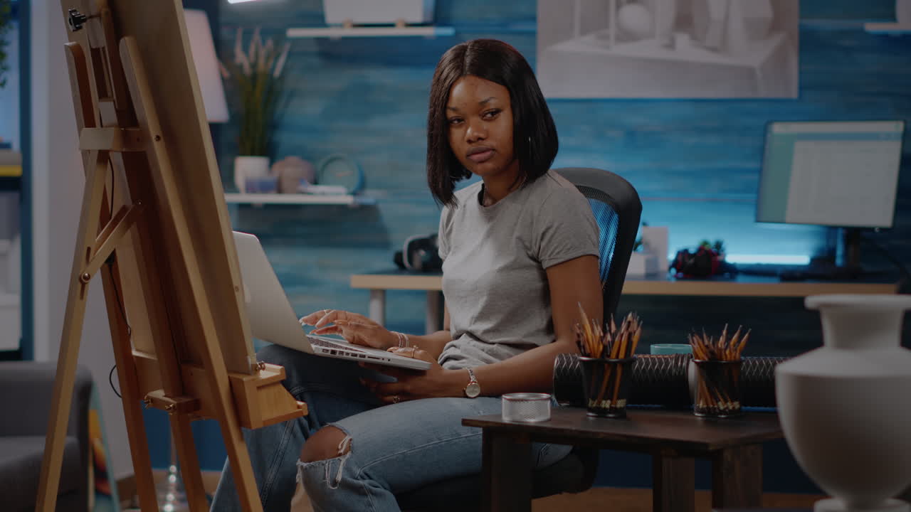 African american artist typing on laptop computer at studio