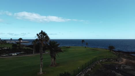 aerial dolly forward of golf course overlooking blue ocean water on coast of spain