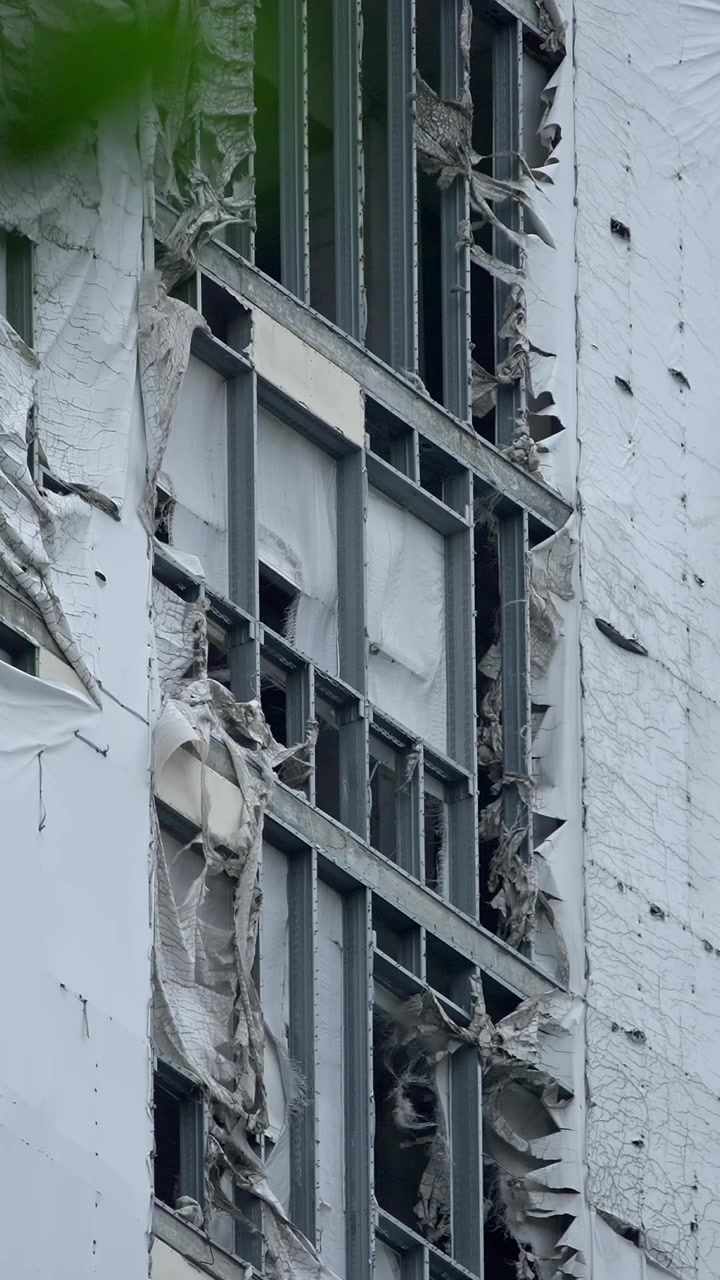Torn White Protective Sheeting Flapping on a Building Under Demolition
