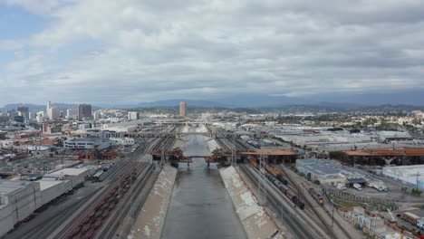 AERIAL:-View-over-Los-Angeles-River-Bridge-Being-Built-under-Construction-Site-with-Overcast-Cloudy-Sky