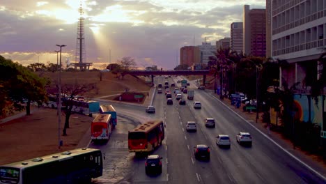 lapso de tiempo de tráfico de carretera de la ciudad al atardecer con nubes y rayos de sol sobre una torre de transmisión de televisión - paisaje de nubes de lapso de tiempo