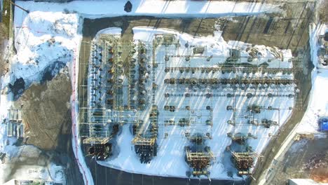 toma aérea descendente cinematográfica de arriba hacia abajo del sitio de la estación transformadora de suministro de energía eléctrica cubierto de nieve en la fría mañana de invierno, canadá