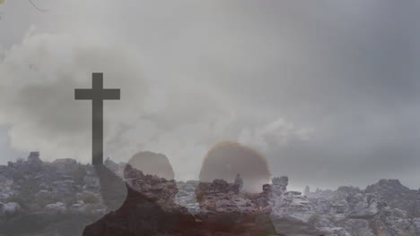 silhouette of person with cross in animation over rocky landscape and cloudy sky