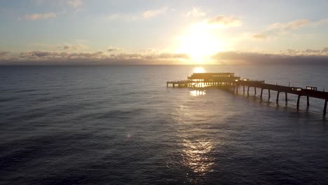 Beautiful-warm-sunrise-horizon-aerial-view-above-idyllic-Deal-pier-Kent-landmark-rising-pull-back