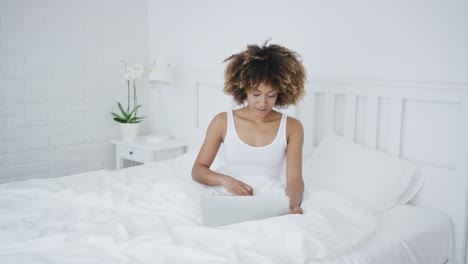 mujer encantadora con laptop en la cama