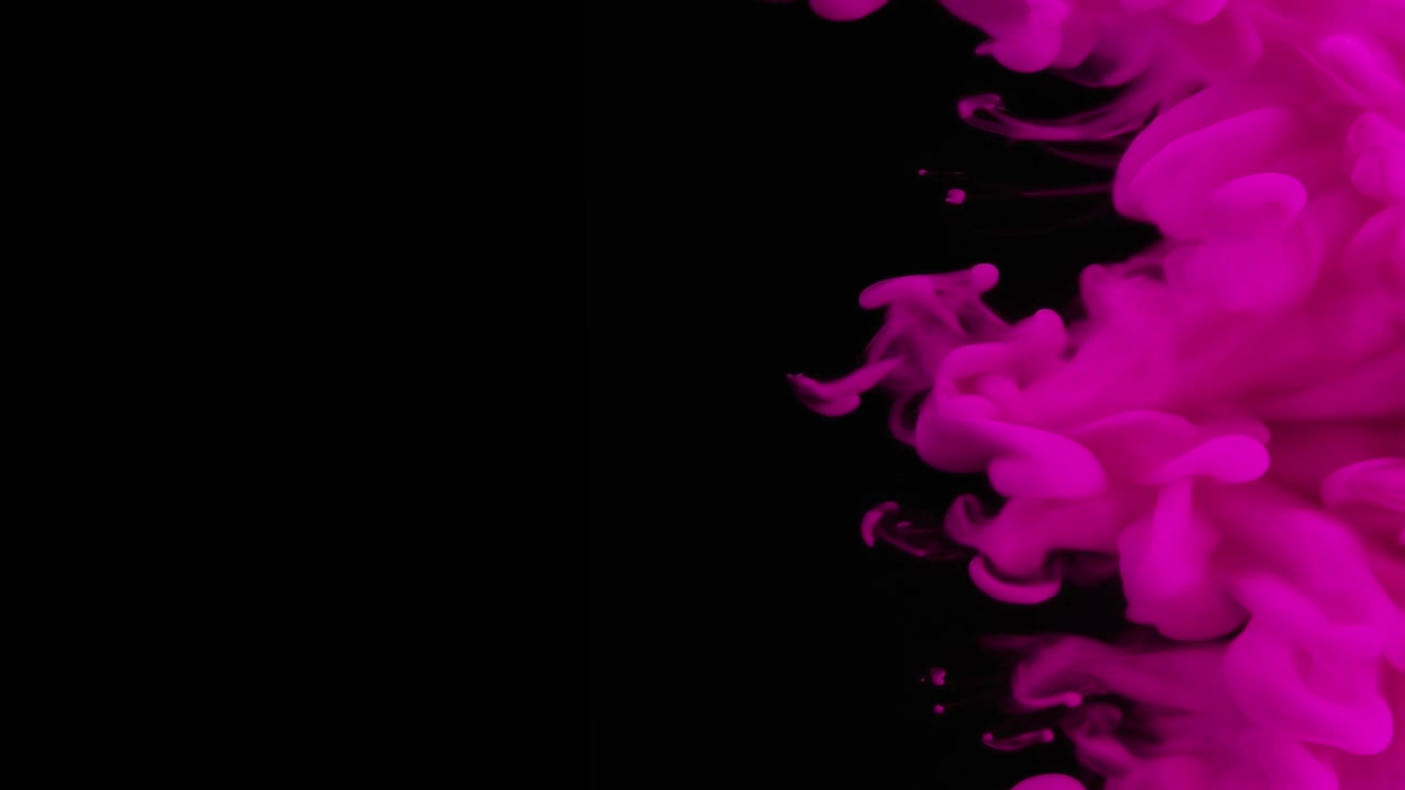 Inchiostro rosa che turbina nell'acqua su sfondo nero