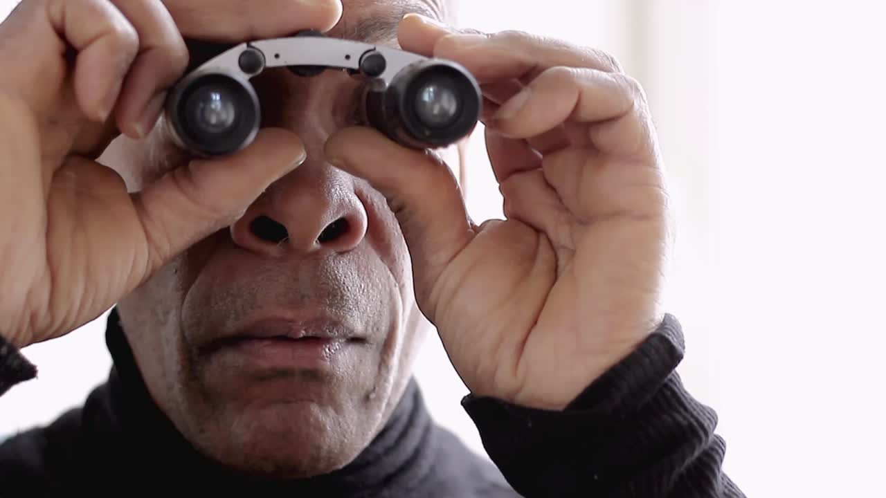 binoculares mirando a través de binoculares con fondo blanco almacen de metraje de video