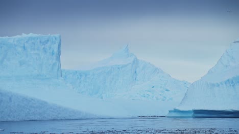 Dramatische-Eisberglandschaft-Mit-Erstaunlichen-Formen-Großer-Blauer-Eisberge,-Antarktische-Landschaft-Mit-Riesigen,-Bizarren,-Wunderschönen-Eisbergen-Im-Meerwasser-Des-Ozeans-In-Einer-Kalten-Winterlandschaft