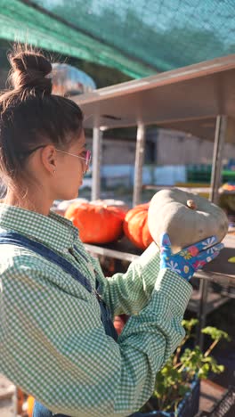 woman examining pumpkin at a farmer's market