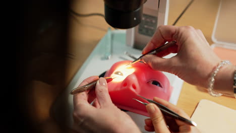 hands holding the forceps and using them on face model. practice on ophthalmic procedure under microscope. close up.