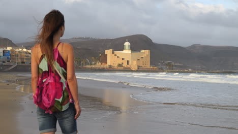 cinematic shot of a woman admiring the alfredo kraus auditorium from las canteras beach, on the island of gran canaria-1