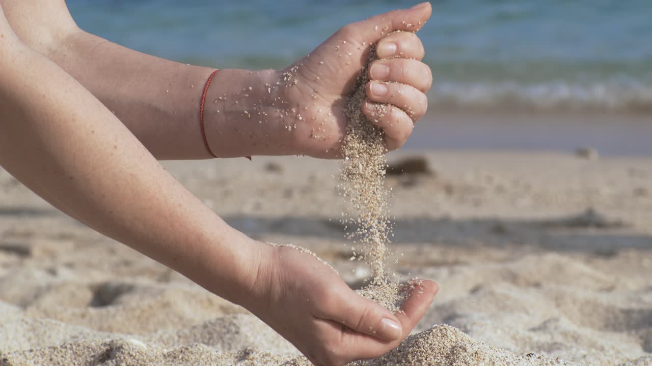 Sand falling from hand in slow motion on a beach. Vacation and travel concept. Shot on super slow motion camera 1000 fps.