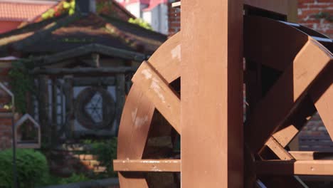 wooden watermill working. rolling wheels of water mill in sunny daytime, red brick wall