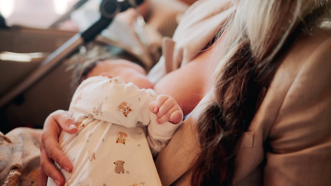 Tender moment of a mother holding her newborn baby dressed in patterned white pajamas