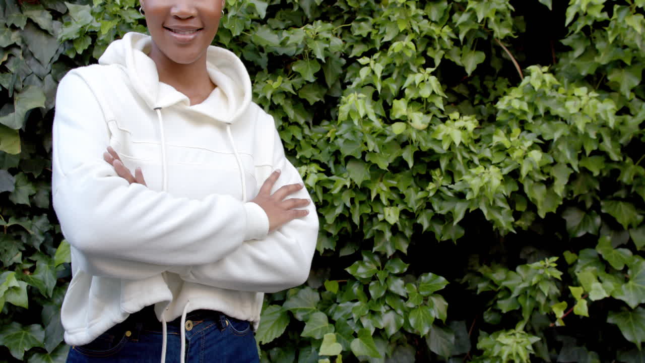 Plano médio de mulher afro-americana com moletom branco com capuz no jardim, espaço para cópia, em câmera lenta