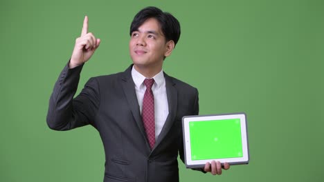 디지털 태블릿을 사용하는 젊은 잘생긴 아시아 사업가