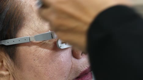 woman with some age fitted eye test glasses carefully to know her vision problem, bangkok, thailand